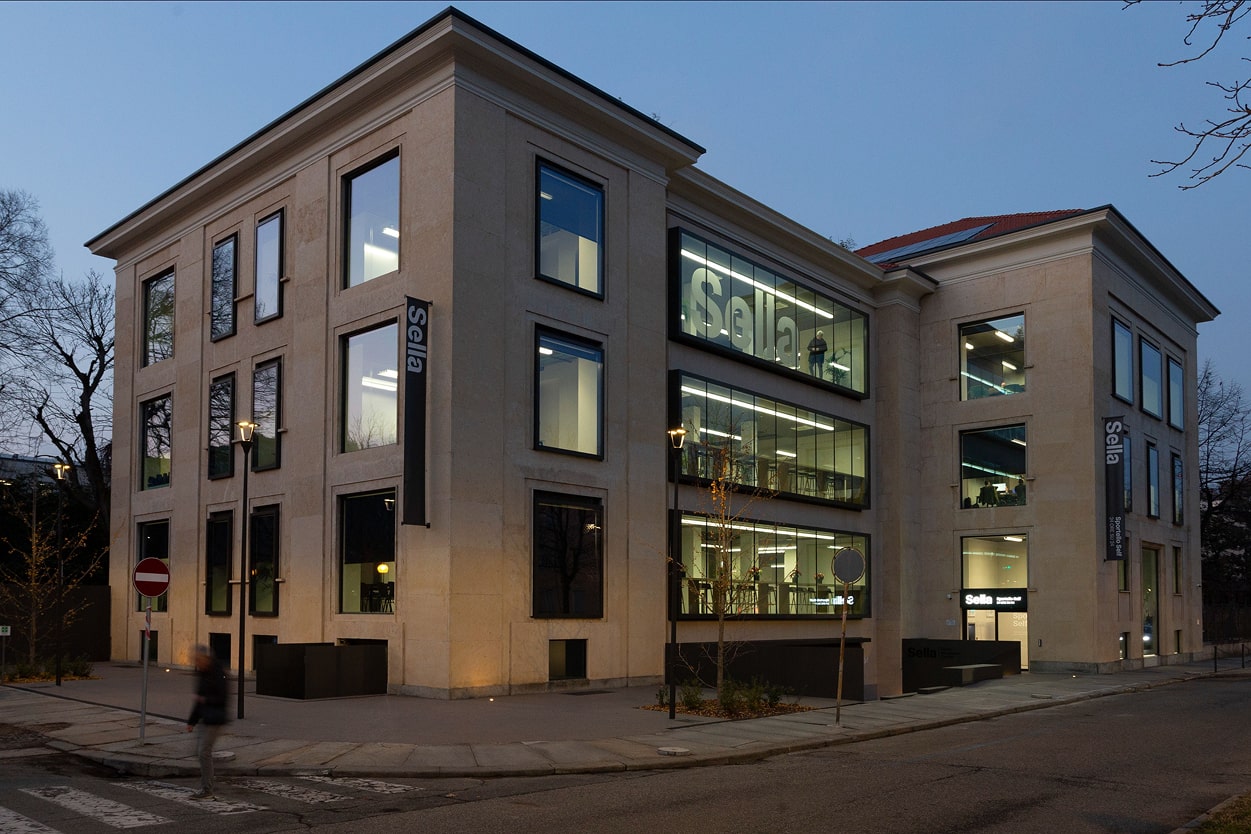 Sede Sella in un edificio a più piani con facciata in pietra e grandi finestre luminose su strada.