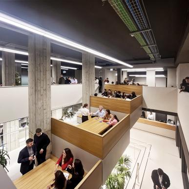 Spazio a gradoni in legno affollato da persone durante un evento aziendale.