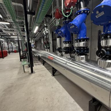 Tubazione industriale in acciaio inox con valvole blu e rosse all’interno di un impianto tecnico.