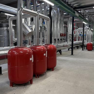 Tre serbatoi rossi in un impianto industriale con tubazioni in acciaio inox.