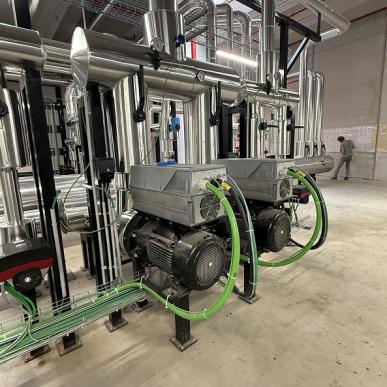 Motori elettrici collegati a tubazioni in acciaio inox in un impianto industriale.